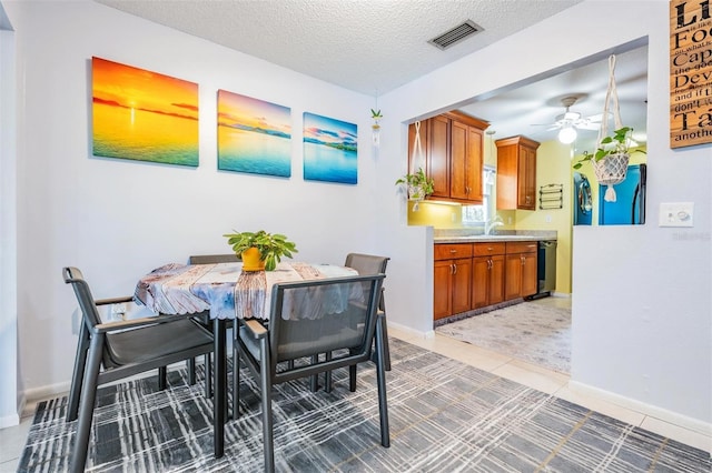 dining space with ceiling fan, sink, a textured ceiling, and tile patterned floors