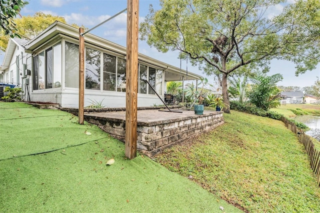 view of home's exterior featuring a patio, a lawn, and a sunroom