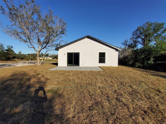 back of property with a yard and a patio