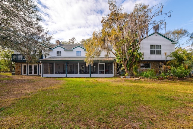 rear view of property with a sunroom and a lawn