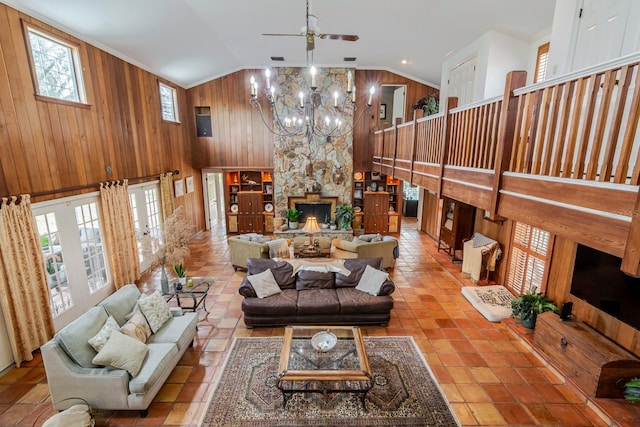 living room featuring an inviting chandelier, plenty of natural light, wooden walls, and a stone fireplace