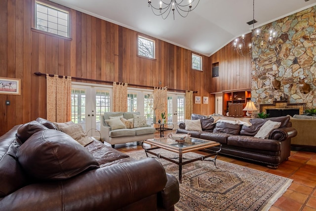 living room with light tile patterned floors, high vaulted ceiling, a notable chandelier, a fireplace, and french doors