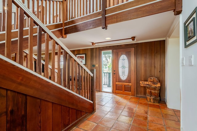 entrance foyer with crown molding and wooden walls