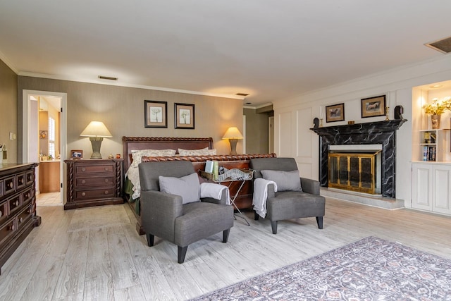 bedroom with ornamental molding, a fireplace, and light hardwood / wood-style floors