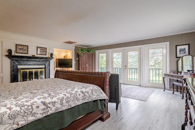 bedroom with crown molding, a high end fireplace, light hardwood / wood-style flooring, and access to outside