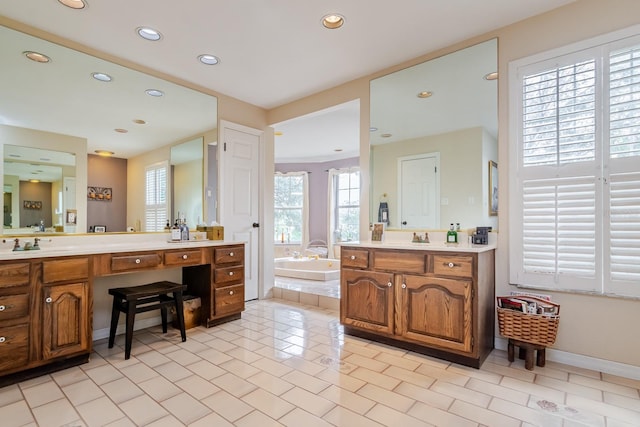 bathroom featuring tile patterned flooring, vanity, and tiled bath