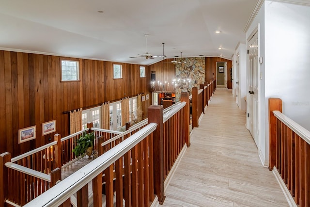 hallway featuring vaulted ceiling, ornamental molding, and light wood-type flooring