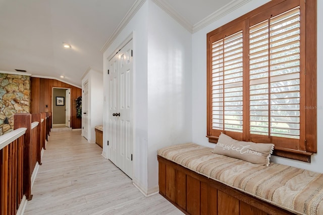 hallway featuring light hardwood / wood-style flooring, ornamental molding, a healthy amount of sunlight, and vaulted ceiling