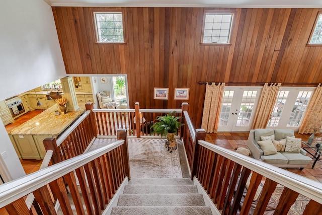 stairs featuring french doors, carpet floors, and wood walls