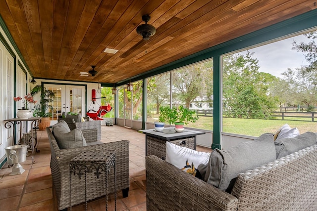 sunroom / solarium featuring a wealth of natural light, wood ceiling, ceiling fan, and french doors