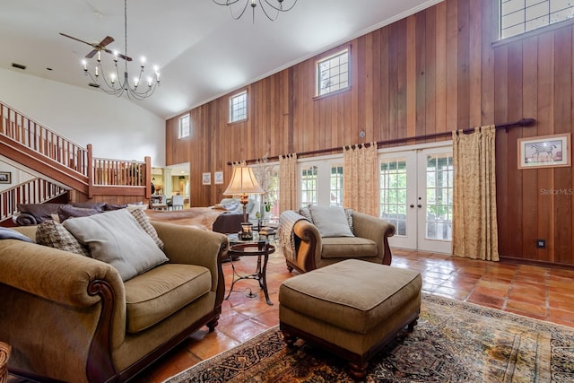 tiled living room featuring french doors, wooden walls, a chandelier, and a high ceiling