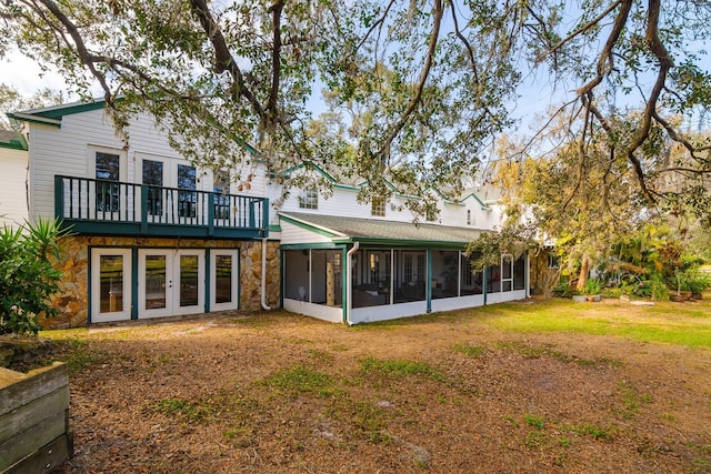 rear view of property featuring french doors, a sunroom, and a lawn