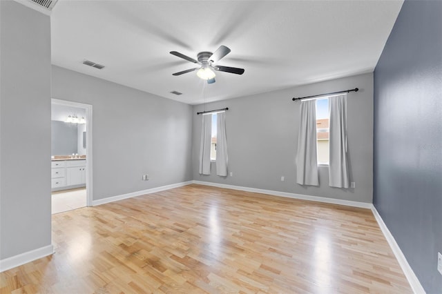 empty room with baseboards, visible vents, and light wood finished floors