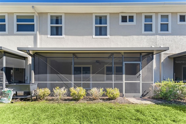 rear view of house with a sunroom and stucco siding