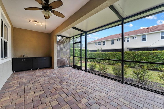 unfurnished sunroom with ceiling fan