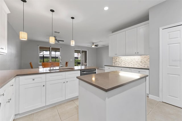 kitchen featuring light tile patterned floors, a peninsula, a sink, stainless steel dishwasher, and decorative backsplash