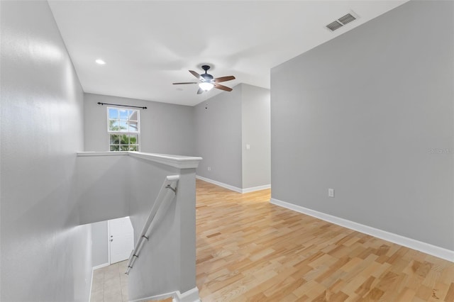 empty room featuring light wood-type flooring, baseboards, visible vents, and a ceiling fan