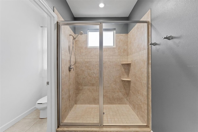 bathroom with a stall shower, baseboards, toilet, and tile patterned floors