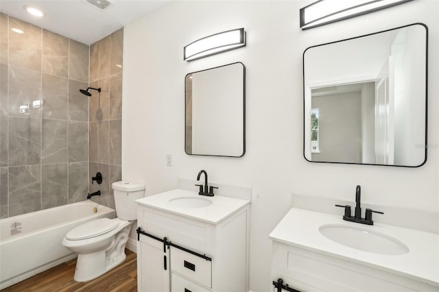 full bathroom with vanity, wood-type flooring, toilet, and tiled shower / bath