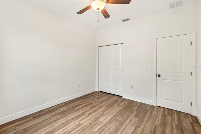 unfurnished bedroom featuring ceiling fan, hardwood / wood-style floors, and a closet