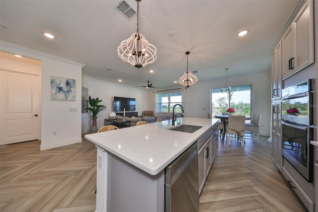 kitchen featuring sink, stainless steel appliances, light parquet floors, and a center island with sink