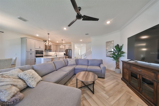 living room featuring sink, light parquet floors, ceiling fan, ornamental molding, and a textured ceiling