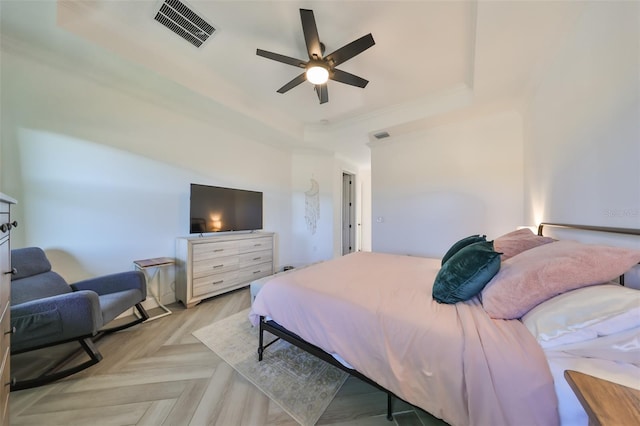 bedroom with ceiling fan, ornamental molding, a raised ceiling, and light parquet floors