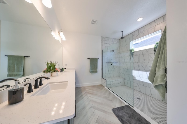 bathroom with parquet floors, vanity, and a tile shower