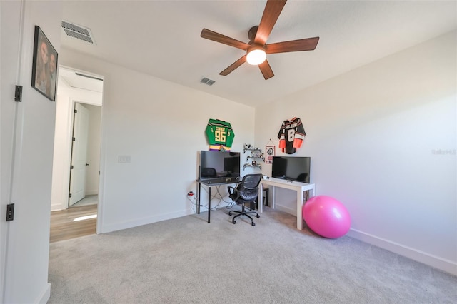 carpeted office space with ceiling fan