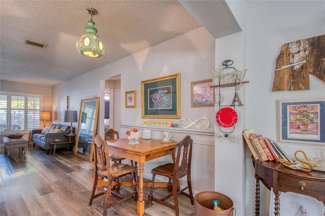 dining space with wood-type flooring and a textured ceiling