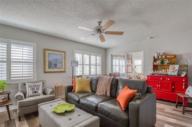 living room with a textured ceiling, ceiling fan, and light hardwood / wood-style flooring