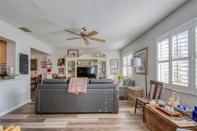 living room with ceiling fan, hardwood / wood-style floors, and a textured ceiling