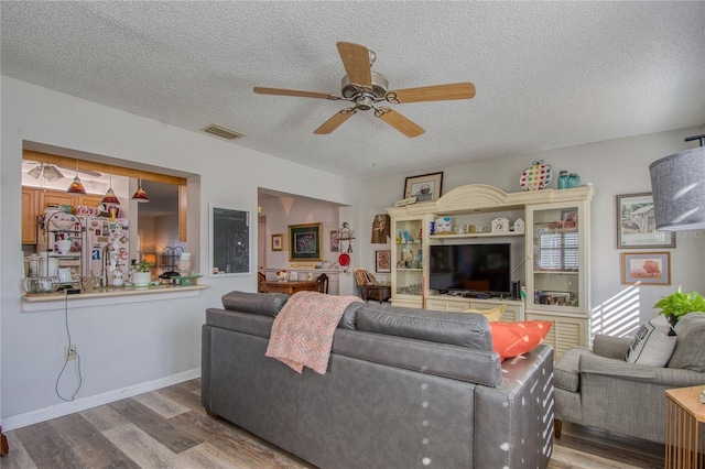 living room featuring a textured ceiling, wood-type flooring, and ceiling fan