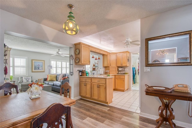 kitchen with a healthy amount of sunlight, light wood-type flooring, hanging light fixtures, and a textured ceiling