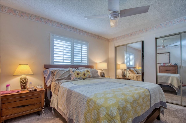 carpeted bedroom featuring ceiling fan, a textured ceiling, and two closets