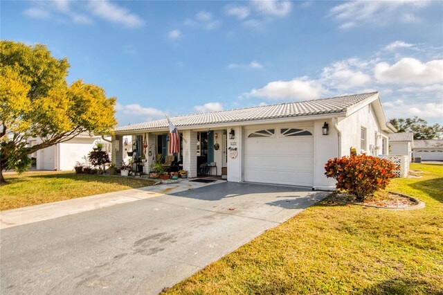 single story home featuring a garage, covered porch, and a front lawn