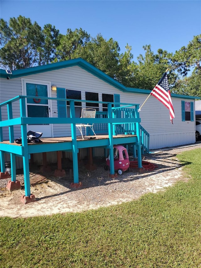 rear view of property featuring a lawn and a deck