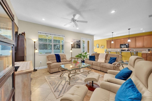 tiled living room with ceiling fan and a textured ceiling