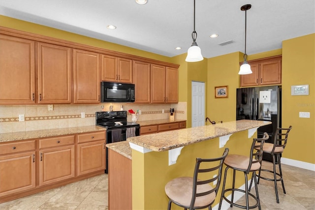 kitchen with a kitchen breakfast bar, tasteful backsplash, light stone countertops, black appliances, and a kitchen island