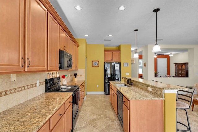 kitchen featuring pendant lighting, sink, backsplash, a kitchen breakfast bar, and black appliances