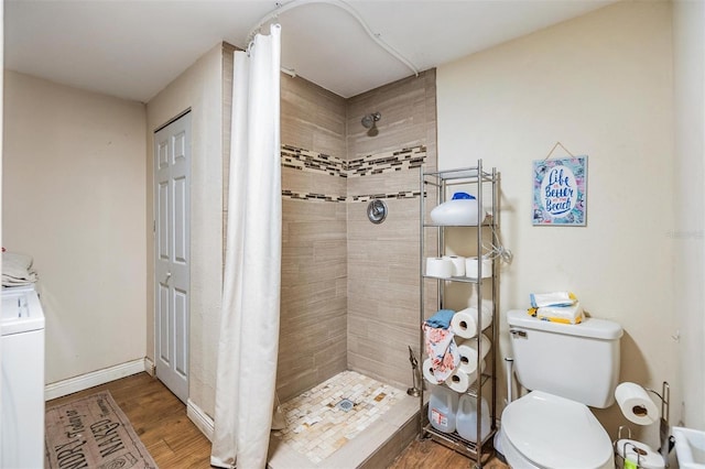 bathroom with a shower with curtain, hardwood / wood-style floors, toilet, and washer / clothes dryer