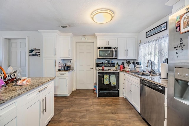 kitchen featuring a textured ceiling, white cabinets, stainless steel appliances, sink, and light stone counters