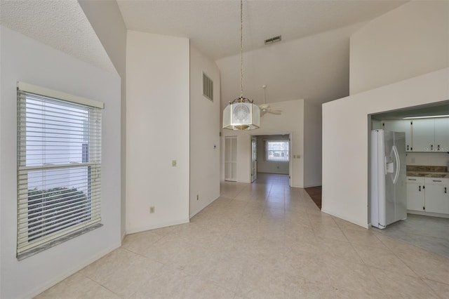 interior space with high vaulted ceiling, light tile patterned floors, and a textured ceiling