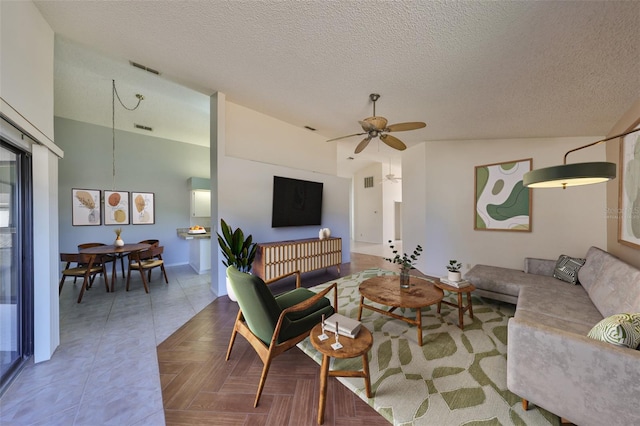 living room featuring ceiling fan, parquet flooring, vaulted ceiling, and a textured ceiling