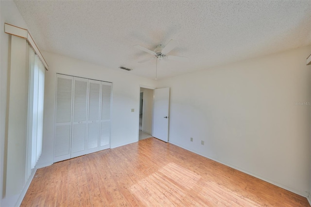 unfurnished bedroom featuring a closet, a textured ceiling, ceiling fan, and light hardwood / wood-style floors