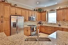 kitchen featuring stainless steel appliances, tasteful backsplash, light stone countertops, and sink