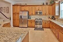 kitchen with tasteful backsplash, light stone countertops, appliances with stainless steel finishes, and kitchen peninsula