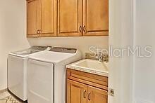 clothes washing area featuring sink, washer and clothes dryer, and cabinets