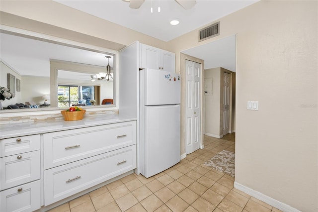 kitchen featuring ceiling fan with notable chandelier, white cabinetry, light tile patterned floors, and white fridge