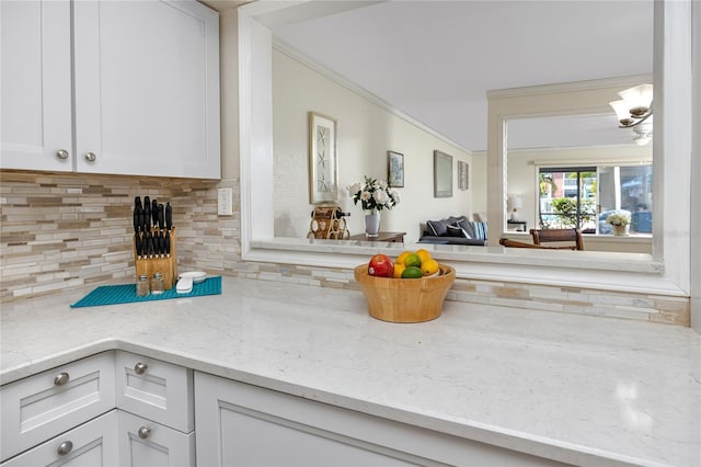 kitchen featuring crown molding, backsplash, white cabinets, and light stone countertops